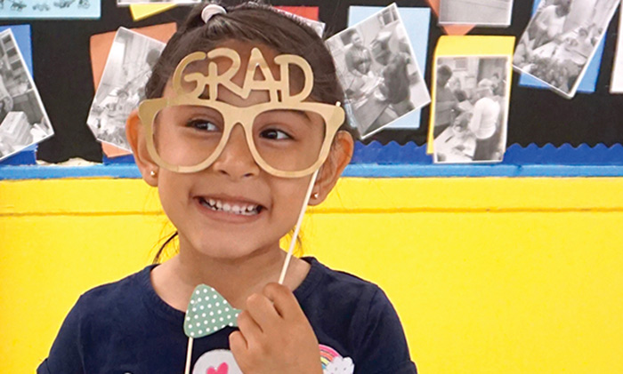 A young girl wearing fun glasses with the word Grad written on them.